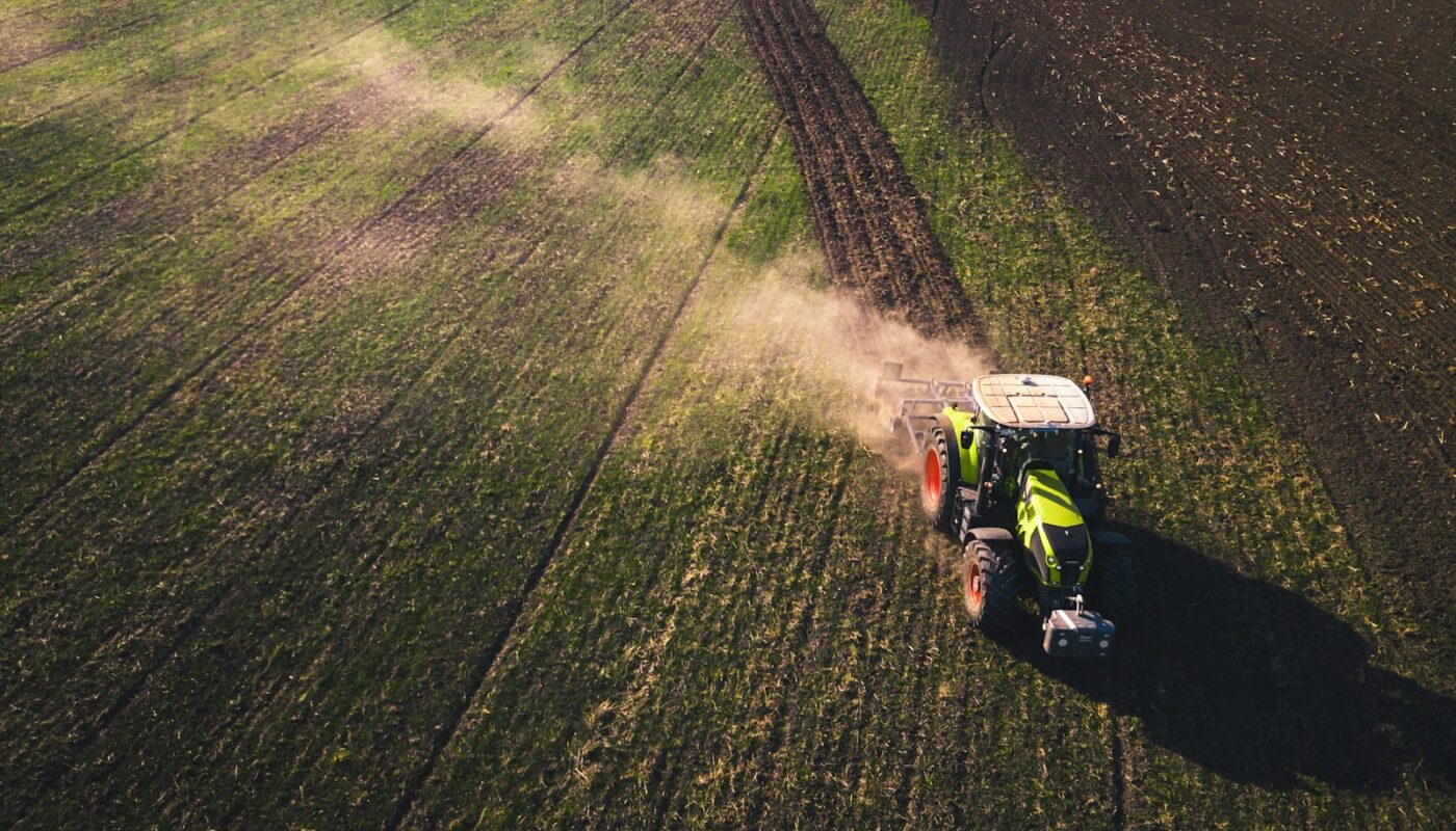 green and white tractor on green grass field during daytime