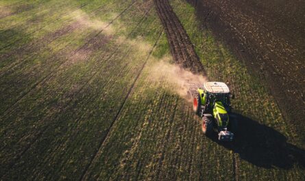 green and white tractor on green grass field during daytime